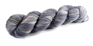 skein of hand dyed wool yarn for knitting and crochet in shades of gray and gold speckles lunar lander space color theme