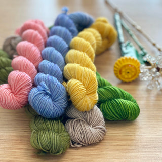 January monthly Color Story Hand Dyed mini skein yarn club subscription from The Woolly Dragon, shown in a pile with Lego flowers.