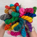 Brightly colored hand-dyed mini skeins arranged like a bouquet, highlighting the vibrant color palettes of the Mini Skein Color Story subscription.